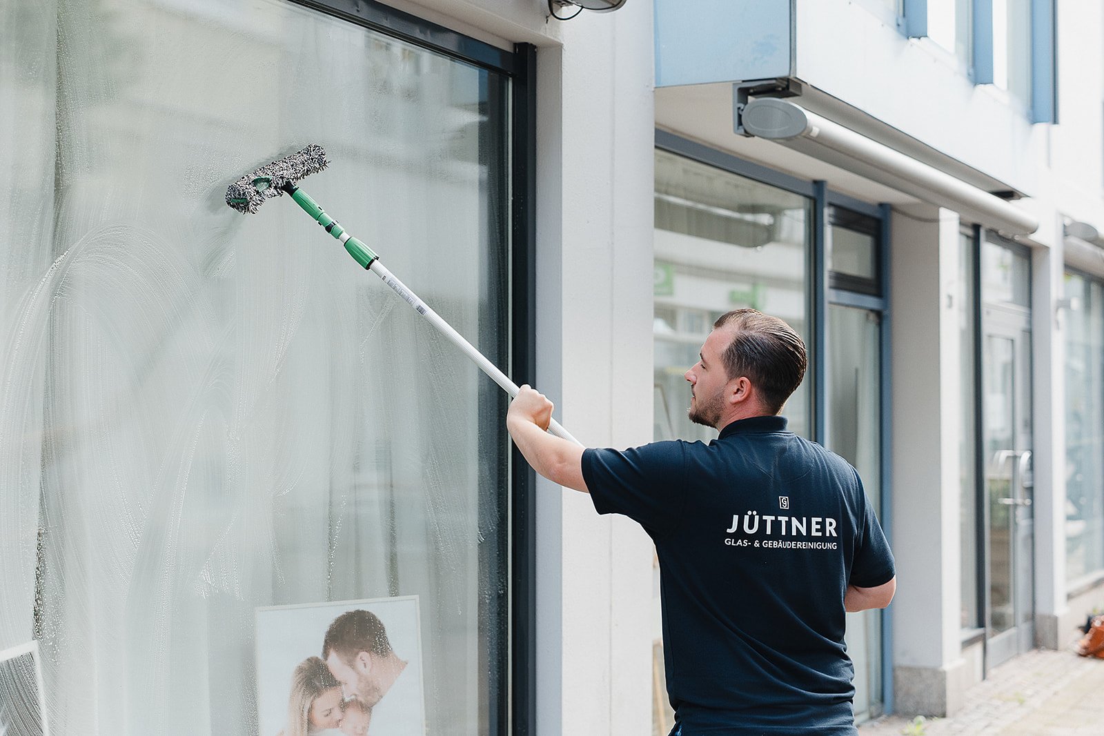 Reinigung eines Schaufensters für ein Geschäft mit Teleskop-Wischer