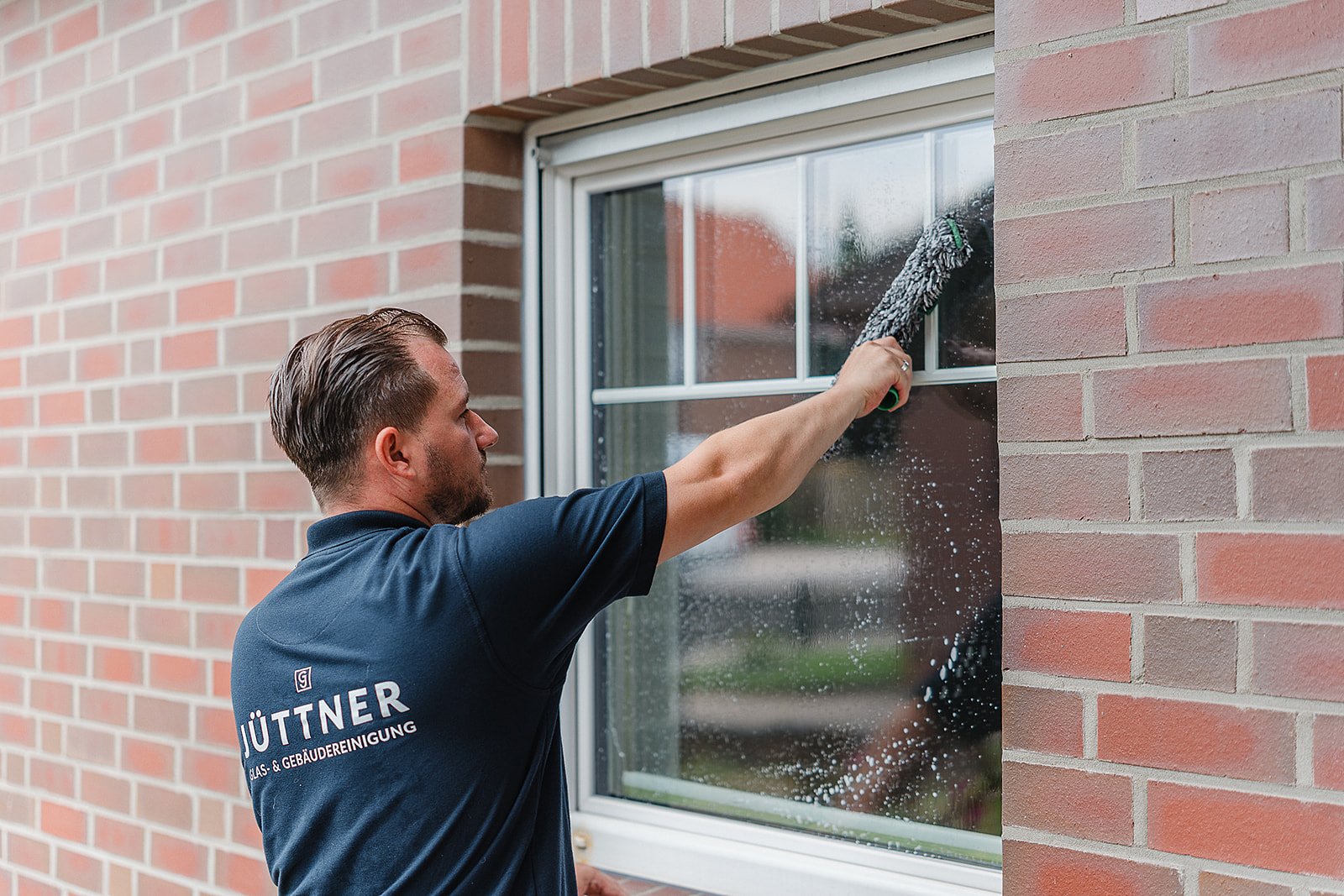Fensterreinigung an einem privaten Wohnhaus mit Teleskop-Wischer