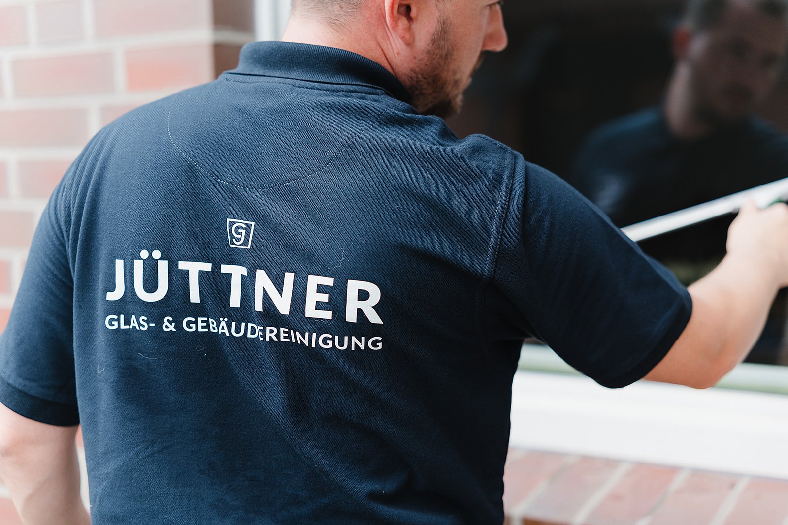 Jüttner Glas- & Gebäudereinigung — Logo auf der Arbeitskleidung